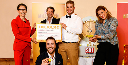 Millionäre halten Geldkoffer, Geldcheck und Loskugel in ihren Händen