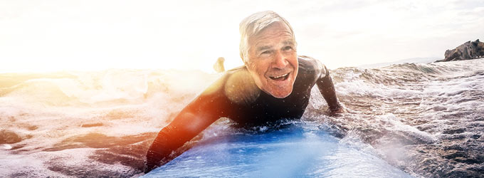 Älterer Mann auf Surfbrett im Meer
